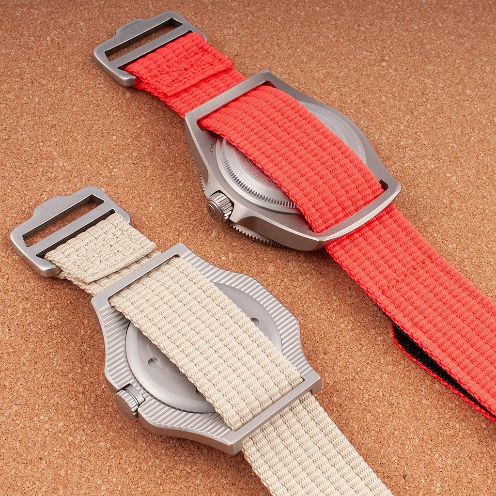 Two watches on hook-and-loop single-pass straps in khaki and red showing caseback and StrapHabit buckle